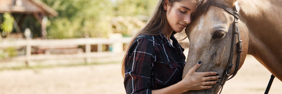 Care, tenderness and animals concept. Lovely and carefree tender young woman in checked shirt, lean on horse face, close eyes and smiling gently, petting pet nose, enjoy weekends on rancho.